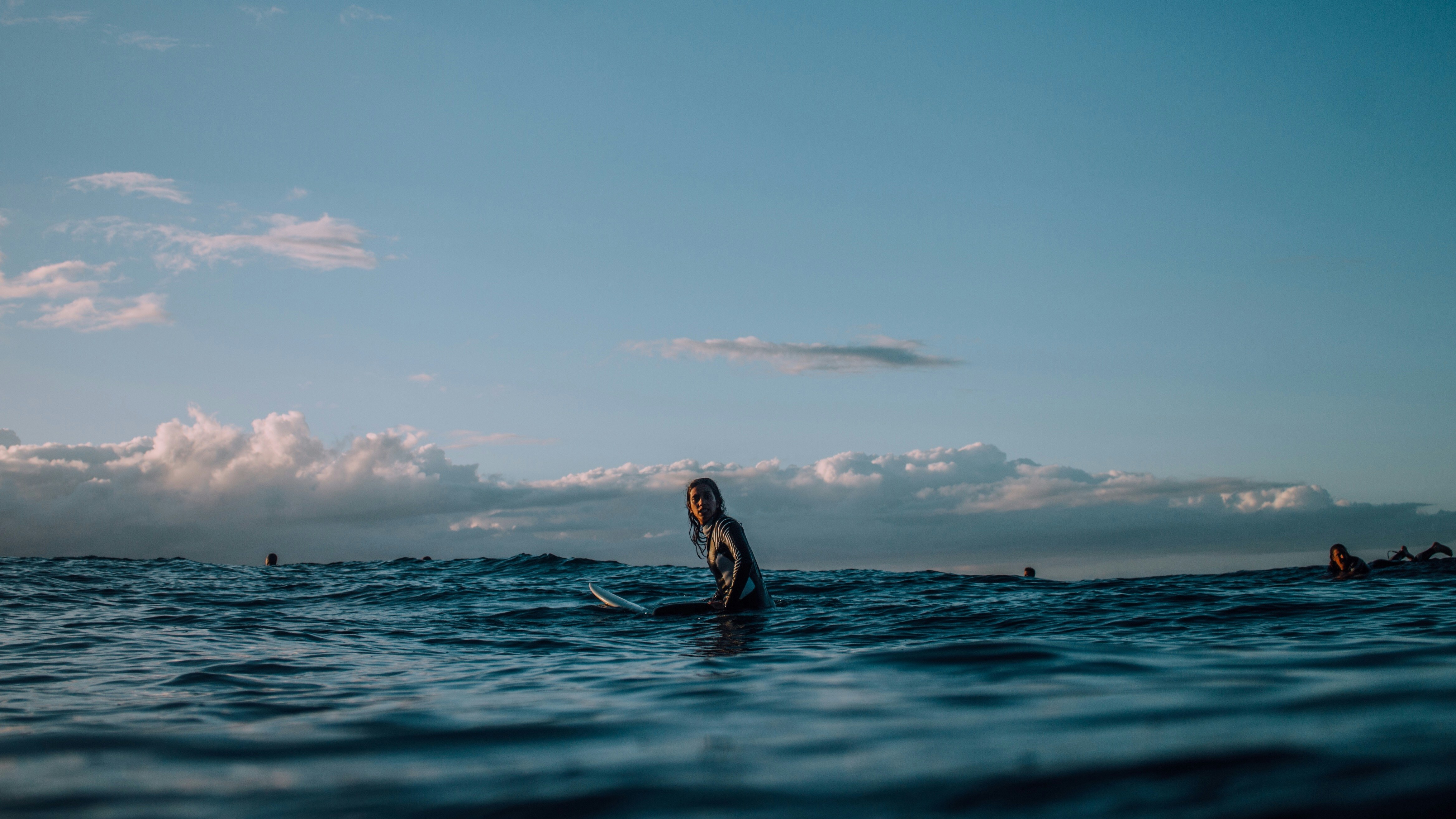 person sitting on surfboard surrounded by blue ocean during daytime